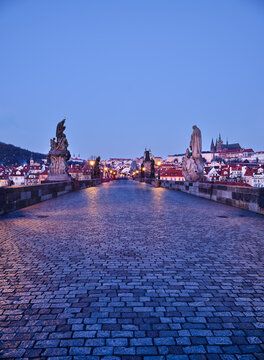 Statues on empty Charles Bridge with Prague Castle at dawn