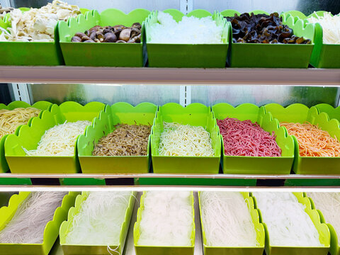Assorted Wok Ingredients on Display in Asian Restaurant &ndash; Fresh Mushrooms, Greens, Sliced Vegetables, Various Noodles, Glass Noodles, Meatballs, Shrimp and Chicken for Custom Stir-Fry