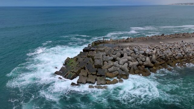 Ocean Surf Rolling Beside a Stone Coastal Breakwater