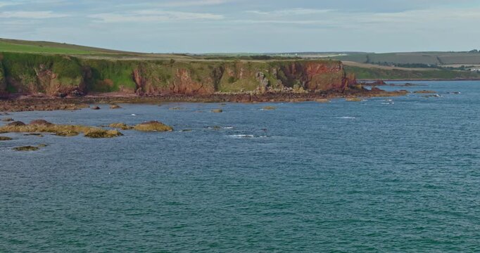 Rugged Coastal Cliffs and Rocky Shoreline Along the Blue Sea in Eyemouth