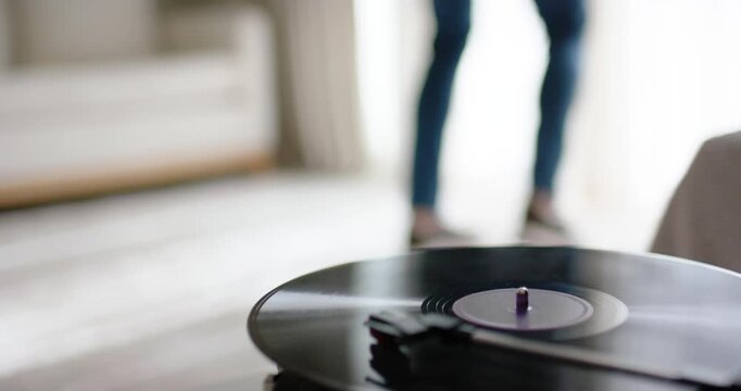 Vinyl is spinning on turntable as person is entering from right and is crossing to exit