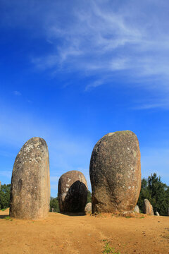 Cromlech of Almendres standing stones. The granite stones are from the megalithic period and are of archaeoastronomical interest. Evora, Portugal. Blue sky with cirrus clouds. Copy space.