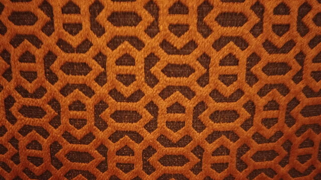 Abstract geometric pattern with intricate interlocking shapes in warm orange and dark brown fabric texture