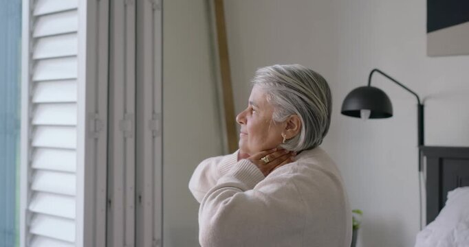 Senior African woman feeling stiff rubbing neck, arching back at home by window, copy space