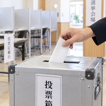 選挙会場で投票用紙を投票箱に入れる手元