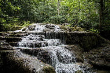 Multi tiered limestone waterfall cascading through lush tropical rainforest in Erawan National Park, Kanchanaburi, Thailand © VaZu Photo