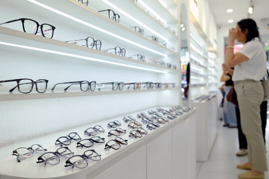 A wide variety of eyeglass frames is displayed on lighted shelves in an optical store, offering customers a wide selection. Ho Chi Minh City, Vietnam.