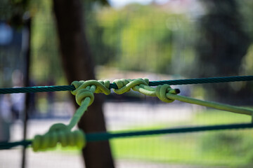 Multiple green rope knots tied around horizontal safety line © Oleksandra Hryshanin