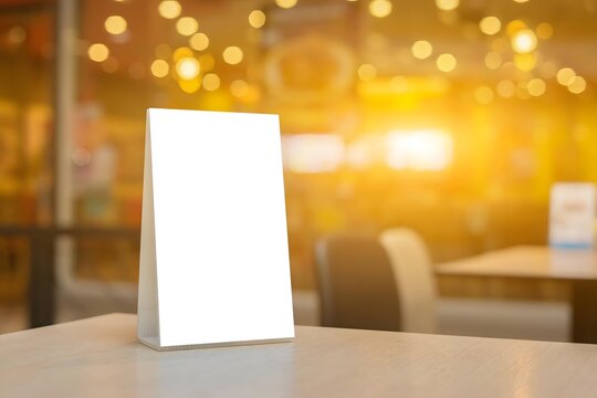 Blank vertical table tent mockup on a restaurant table with warm sunset lighting and bokeh background