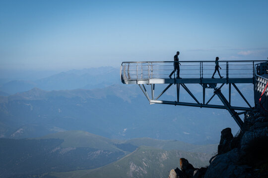 Visitor walking the suspended footbridge over a five hundred metre drop at the Pic du Midi de Bigorre, Pyrenees, France