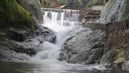 Small Waterfall and Water Dam Structure Flowing Over Rocky Stream in the Forest © Henny