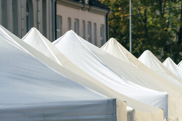 White Market Tent Roofs Forming a Repeating Geometric Pattern at an Outdoor Fair © Edijs