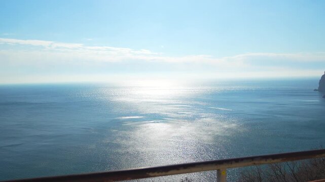 Ocean woman freedom wearing a yellow jacket raises arms while looking at the vast sea from a high cliff top