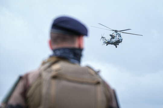 Helicopter passing behind a soldier's shoulder during a special forces demonstration near Bordeaux, France