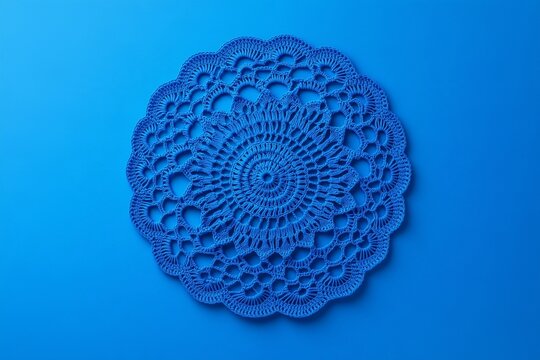 Blue crochet doily with intricate lace pattern on vibrant blue background.