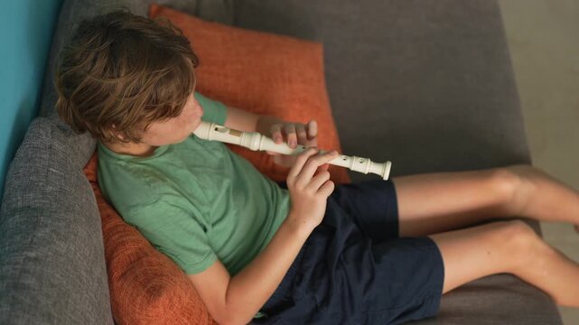 A little boy learns to play the flute at home, practicing with focus and enthusiasm in a cozy, warm setting. A charming scene of early musical exploration, creativity, and childhood growth.