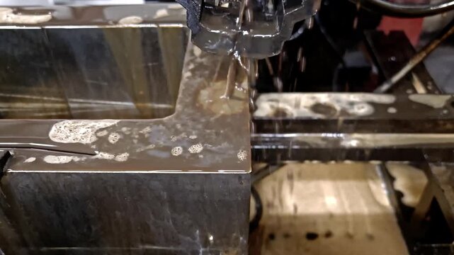 Wire EDM machine cutting steel block with flowing dielectric water