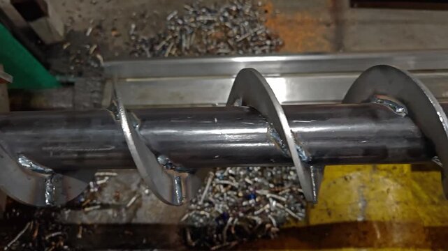 Lathe machining screw conveyor auger with metal chips