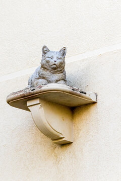Stone Cat Statue on Decorative Wall Shelf Against Textured Beige Stucco Wall