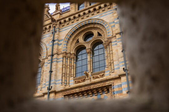 Ornate architecture of London's Natural History Museum viewed through a stone frame.