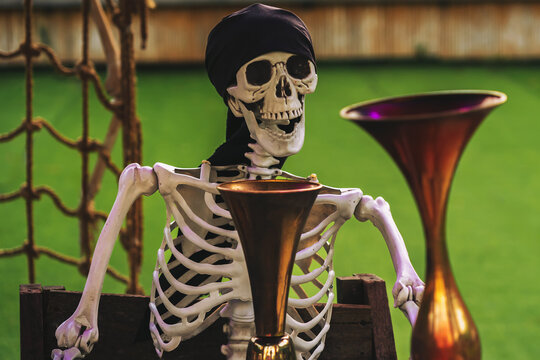 Creepy pirate skeleton prop with black bandana and other ghosts for Halloween outdoor decoration. Ideal concept for outdoor Halloween props, pirate theme party decorations, haunted park attractions,
