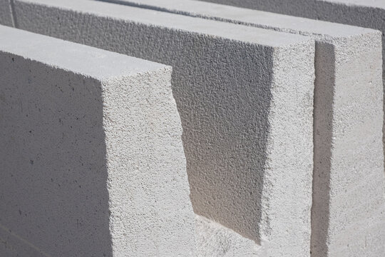 Stacked aerated concrete U-channel lintel blocks for building construction site. masonry units are clearly highlighted under bright natural daylight.