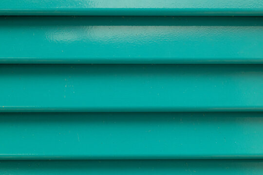 Teal Painted Horizontal Slats Texture Background &mdash; close-up of turquoise louvered surface with glossy paint, parallel grooves and light weathering, full-frame abstract pattern with copy space