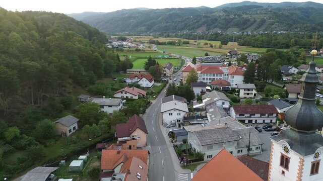 Aerial drone footage of Limbus Parish Church with its distinctive dark onion dome and red tiled roofs in Limbus, Slovenia.