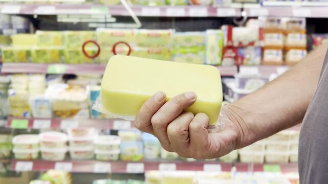 Hand Holding Mozzarella, Suluguni and Burrata Cheese Packages in Supermarket Cheese Section &ndash; Fresh Dairy Products Against Shelves Background