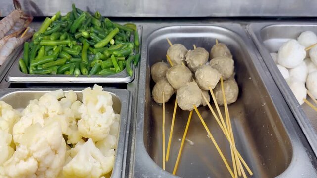 Assorted Wok Ingredients on Display in Asian Restaurant &ndash; Fresh Mushrooms, Greens, Sliced Vegetables, Various Noodles, Glass Noodles, Meatballs, Shrimp and Chicken for Custom Stir-Fry