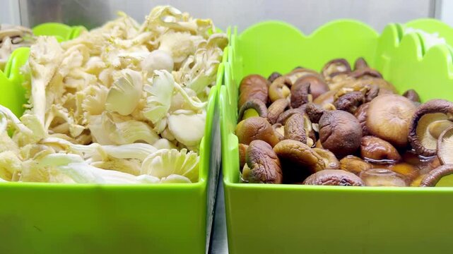 Assorted Wok Ingredients on Display in Asian Restaurant &ndash; Fresh Mushrooms, Greens, Sliced Vegetables, Various Noodles, Glass Noodles, Meatballs, Shrimp and Chicken for Custom Stir-Fry