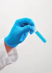Researcher hand with blue protective glove holding test tube containing sample liquid, closeup detail © Lubo Ivanko
