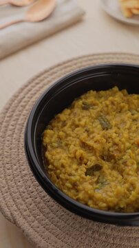 Freshly Cooked Yellow Moong Dal Khichdi with Turmeric Served Hot in a Black Bowl, Close-Up Food Shot.