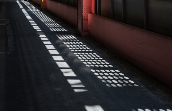 Sunlight Grid Patterns Cast on Asphalt Floor in Parking Lot