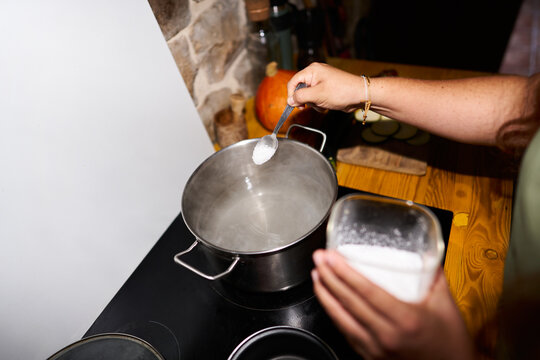 Hand adding salt to boiling water in pot