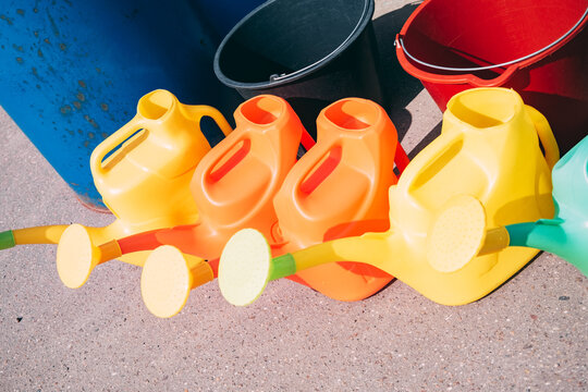 Watering cans and buckets arranged on the ground in an outdoor space