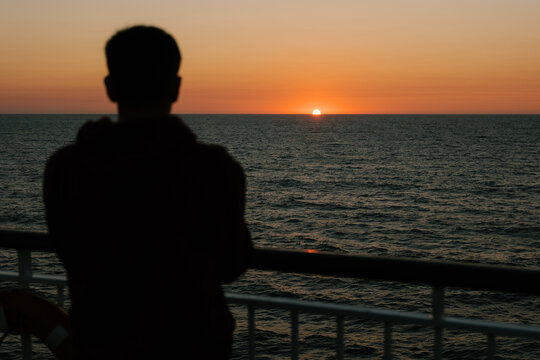 Golden sun setting over calm ocean horizon during a bright evening