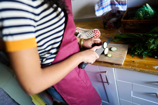 Woman slicing zucchini in kitchen preparing healthy meal