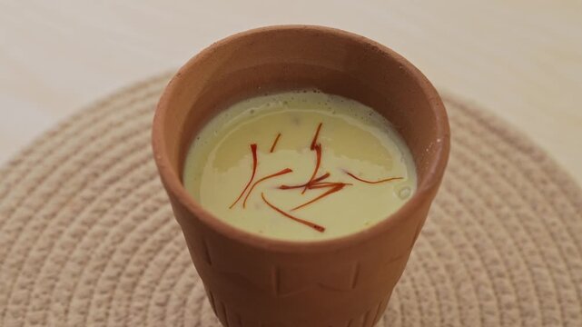 Creamy Traditional Indian Lassi Topped with Saffron Strands Served in a Rustic Clay Cup, Close-Up Beverage Shot