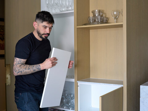 Tradie Arranges Shelving in a Storage Cabinet in a Home Setting