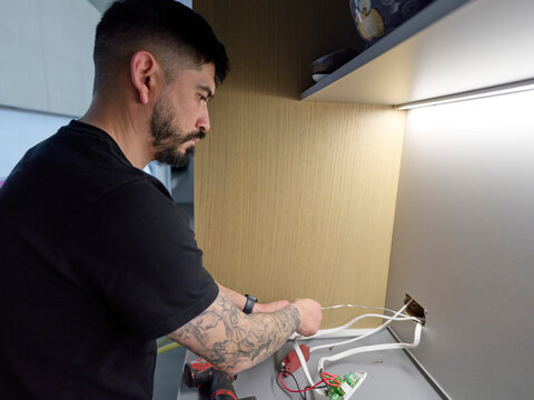 Electrician Feeds Electrical Cable Through Cavity Wall