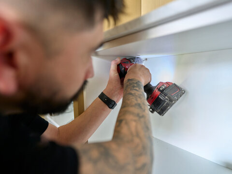 Electrician Installing New Lightning in Small Cabinet