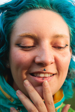Woman smiling with hand touching piercing