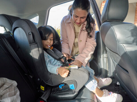 Mother Helps Child With Car Seat Safety