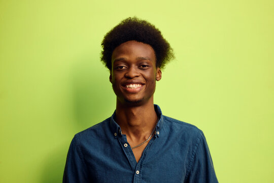 Man smiling in front of a green background