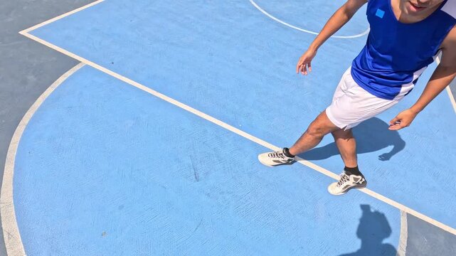 First person perspective of a male basketball player dribbling and shooting on a blue outdoor court during a sunny day with a friend