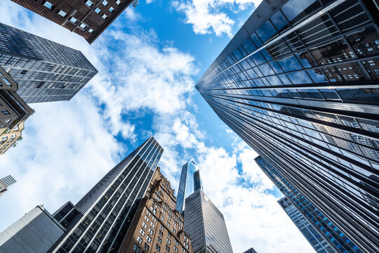 Modern skyscrapers and glass office buildings in business district, captured from low angle perspective with blue sky, symbolizing architecture, urban growth, corporate success, and city development.