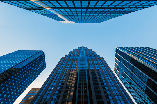 Modern skyscrapers and glass office buildings in business district, captured from low angle perspective with blue sky, symbolizing architecture, urban growth, corporate success, and city development.