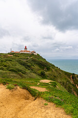Fototapeta premium Cabo da Roca dramatic coastal cliff overlooking Atlantic Ocean in Portugal. Scenic westernmost point of Europe with rugged landscape, ocean waves and natural coastline.