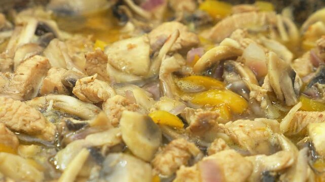 In a deep cast-iron skillet, onions simmer with chicken in a sauce and spices